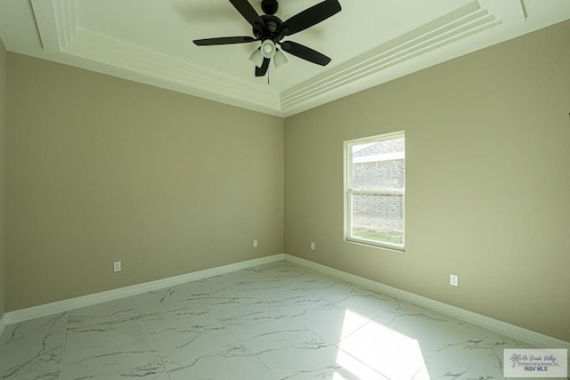 spare room with marble finish floor, ceiling fan, baseboards, and a raised ceiling