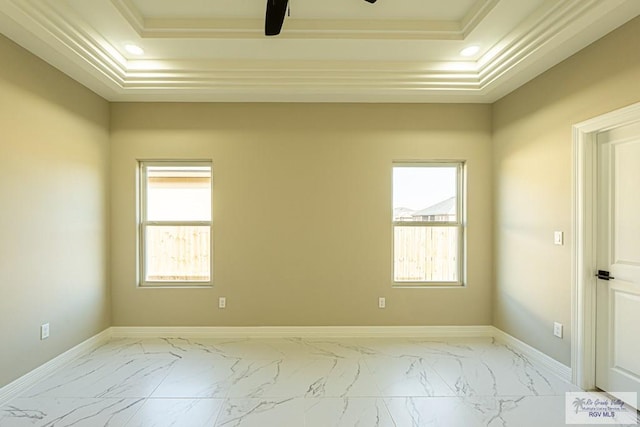 spare room with marble finish floor, a raised ceiling, and baseboards