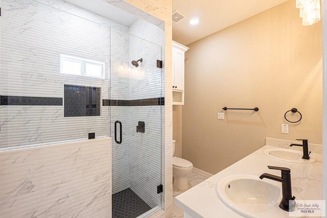 bathroom featuring toilet, a stall shower, and a sink