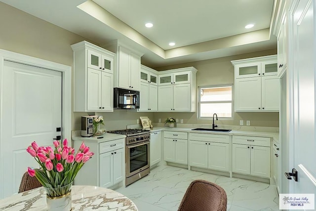 kitchen with black microwave, a sink, marble finish floor, light countertops, and stainless steel range with gas stovetop