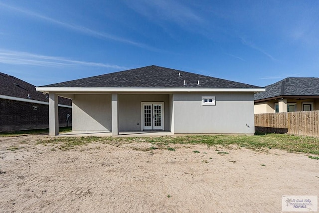 rear view of house with a patio, fence, french doors, roof with shingles, and stucco siding