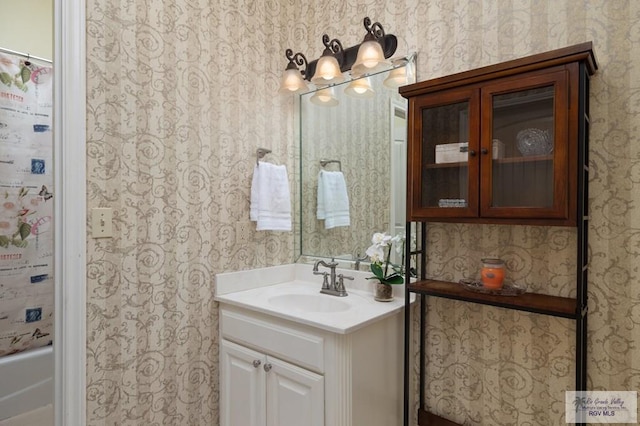 full bathroom with wallpapered walls, a shower with curtain, a washtub, and vanity