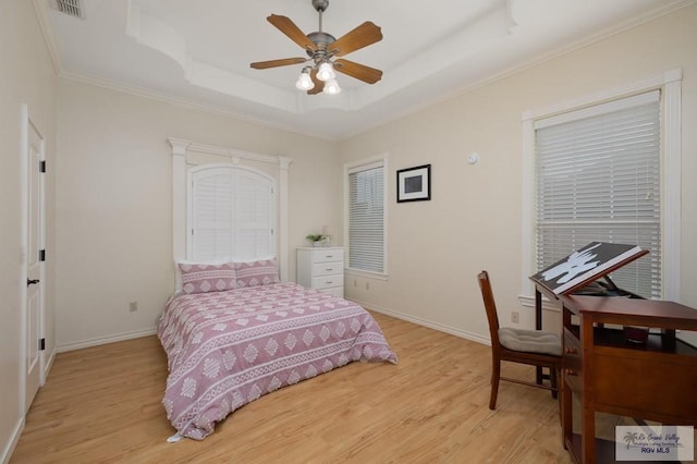 bedroom with light wood-type flooring, a raised ceiling, visible vents, and baseboards