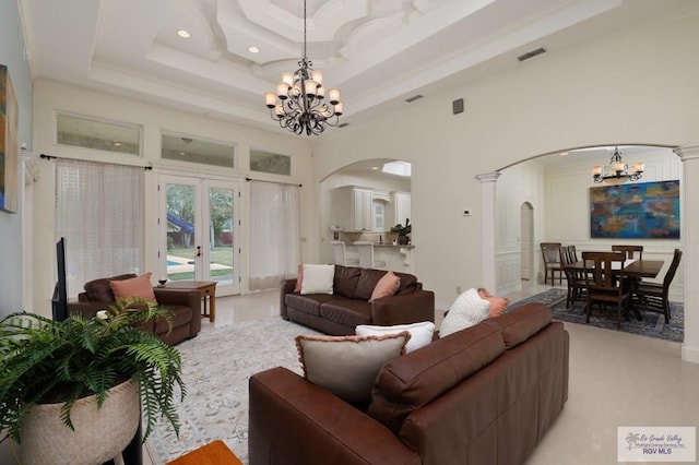 living area featuring visible vents, a chandelier, arched walkways, and a tray ceiling