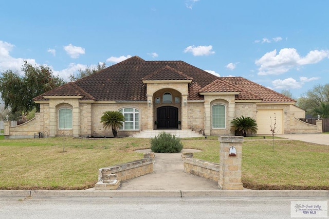 mediterranean / spanish-style home featuring a garage, driveway, a front lawn, and a tile roof