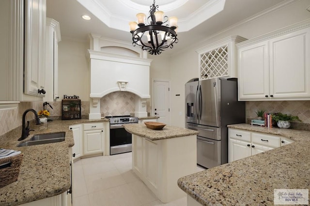 kitchen with crown molding, stainless steel appliances, a sink, and a raised ceiling