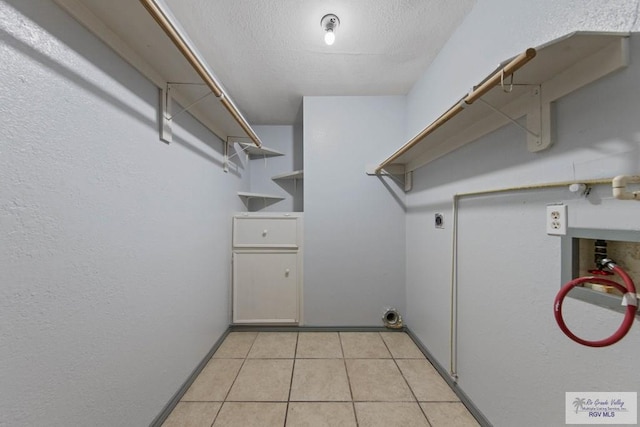 washroom featuring light tile patterned floors, washer hookup, a textured ceiling, and hookup for an electric dryer