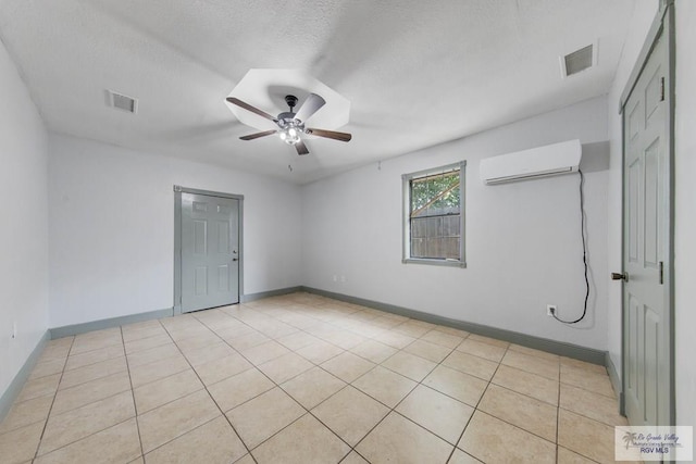 tiled spare room with a wall mounted air conditioner, a textured ceiling, and ceiling fan