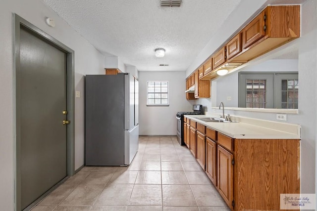 kitchen featuring sink, light tile patterned floors, a textured ceiling, and appliances with stainless steel finishes