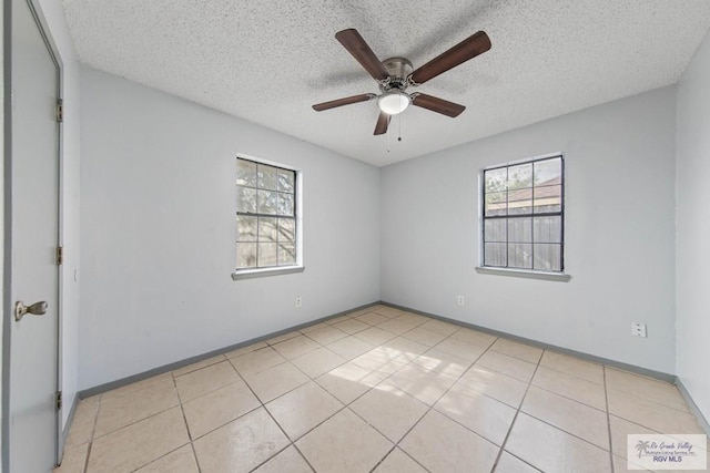 spare room featuring ceiling fan, light tile patterned floors, and a textured ceiling