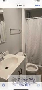 bathroom with curtained shower, vanity, and toilet