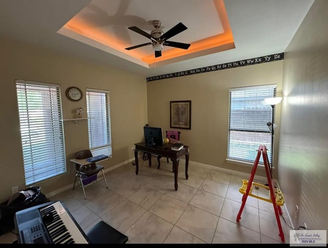 office featuring ceiling fan, baseboards, and a tray ceiling