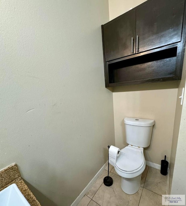 bathroom featuring tile patterned floors, baseboards, and toilet