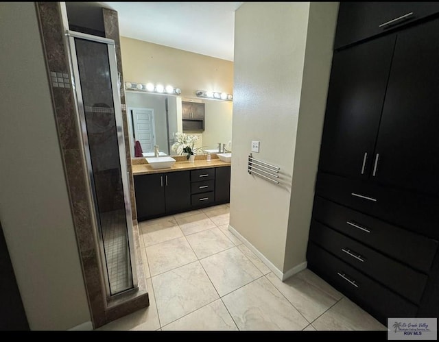 full bath with baseboards, a sink, double vanity, and a stall shower