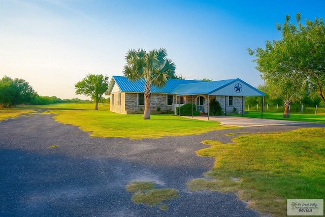 34719 Los Ranchos Rd Unit 1, San Benito, TX 78586 - ranch-style home with stone siding, driveway, a front lawn, a carport, and a metal roof