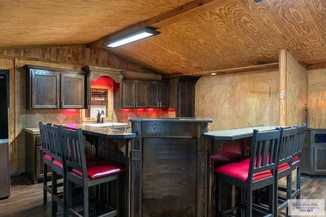 bar featuring wooden ceiling, dark hardwood / wood-style flooring, lofted ceiling, wooden walls, and dark brown cabinets