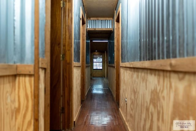 hallway with dark wood-type flooring and wooden walls