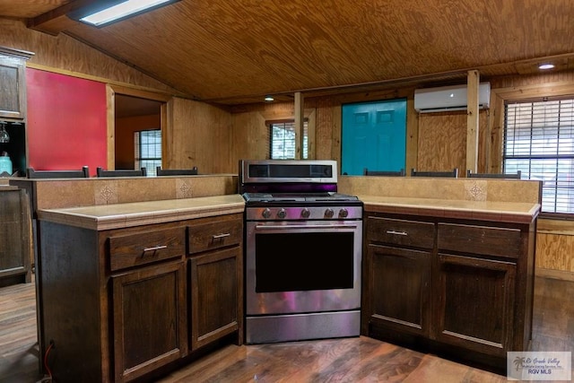 kitchen featuring wood ceiling, a wall unit AC, dark wood-type flooring, stainless steel range oven, and vaulted ceiling with beams