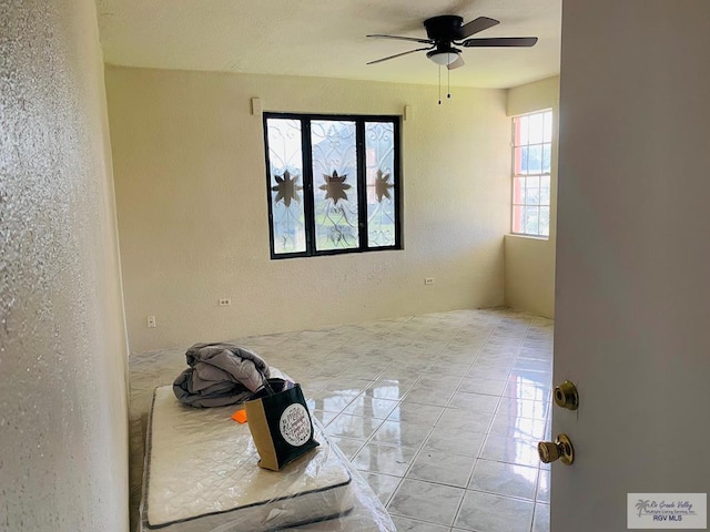 tiled spare room with ceiling fan