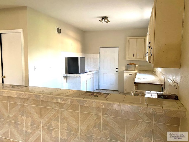 kitchen with cream cabinetry, tile counters, and kitchen peninsula