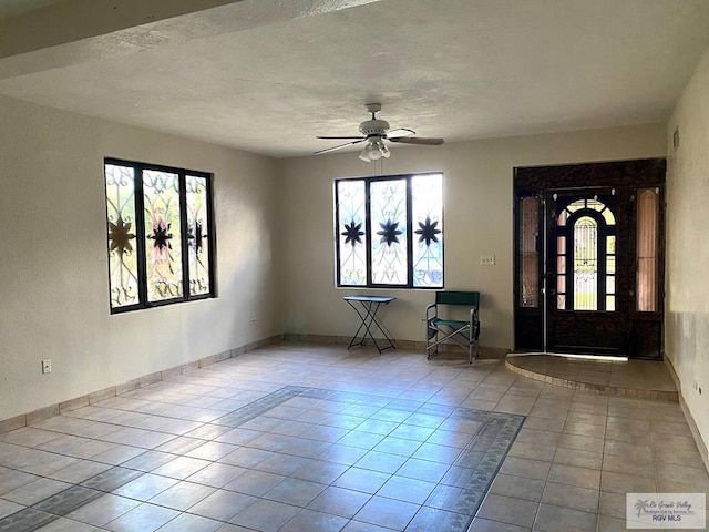 tiled foyer entrance featuring ceiling fan and a textured ceiling