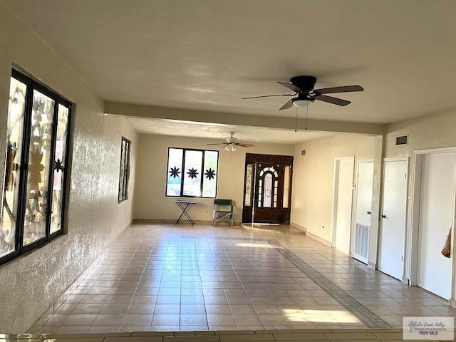 empty room with ceiling fan and light tile patterned floors