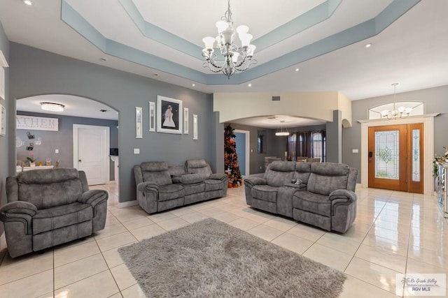 tiled living room with a raised ceiling and an inviting chandelier