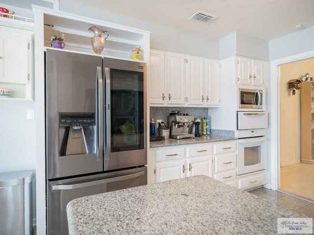 kitchen with light tile patterned flooring, light stone counters, white cabinetry, and stainless steel appliances