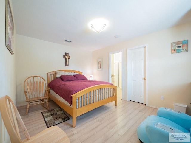 bedroom with connected bathroom and light hardwood / wood-style flooring