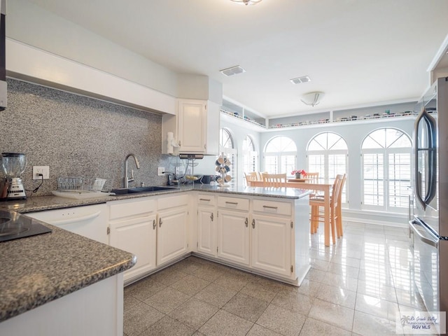 kitchen featuring white cabinetry, backsplash, stainless steel fridge, and kitchen peninsula