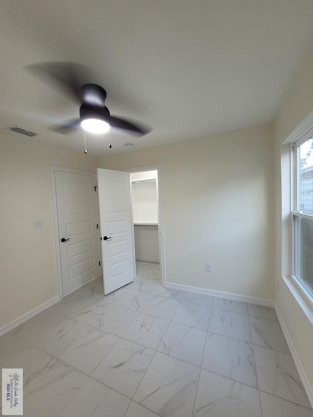 unfurnished bedroom with ceiling fan, a spacious closet, and a closet