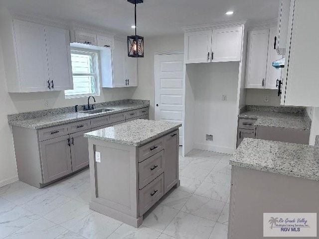 kitchen with sink, a center island, hanging light fixtures, range hood, and white cabinets