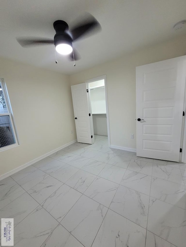 unfurnished bedroom with ceiling fan, a spacious closet, and a closet