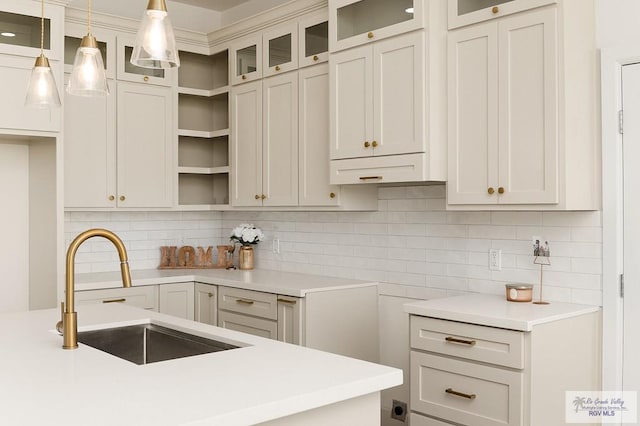 kitchen featuring decorative light fixtures, backsplash, sink, and white cabinetry