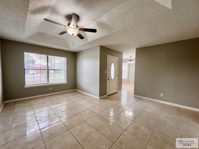 interior space with a textured ceiling, ceiling fan with notable chandelier, and a tray ceiling