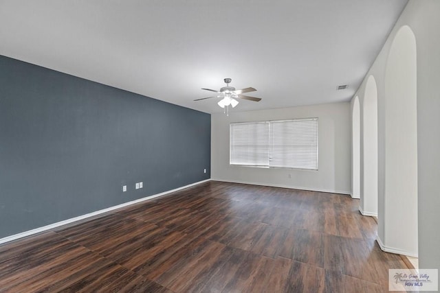 3017 Paradise Ave, Harlingen, TX 78552 - spare room featuring ceiling fan, dark wood-style floors, baseboards, and arched walkways
