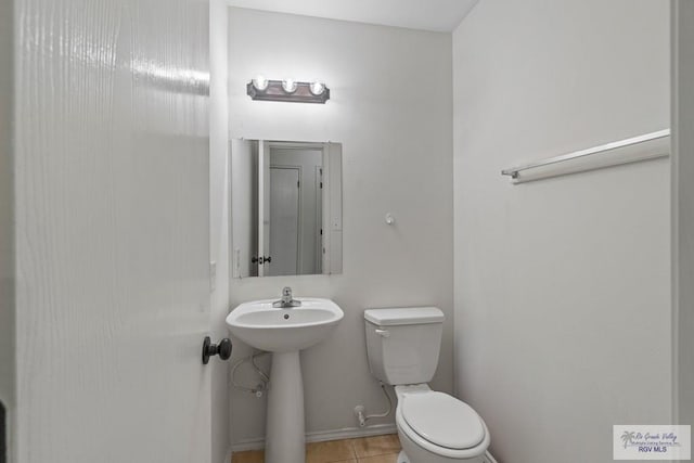 3017 Paradise Ave, Harlingen, TX 78552 - half bathroom with toilet, tile patterned floors, a sink, and baseboards