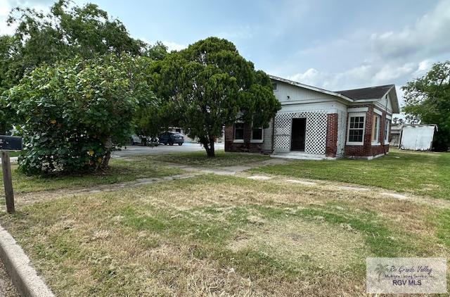 309 E Polk Ave, Harlingen, TX 78550 - view of side of property featuring brick siding and a lawn