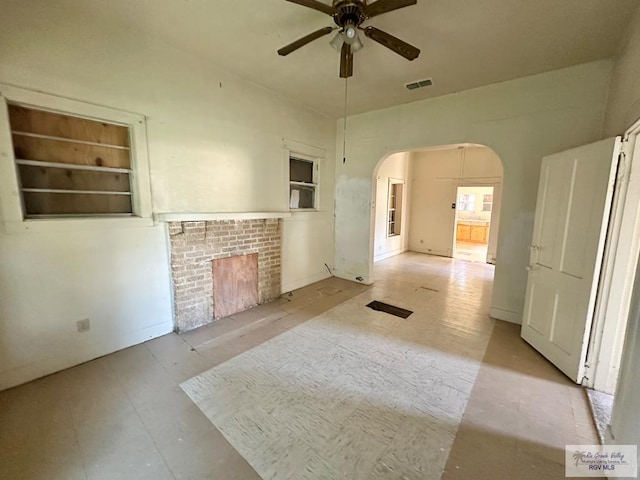 309 E Polk Ave, Harlingen, TX 78550 - unfurnished living room featuring ceiling fan, arched walkways, and a brick fireplace