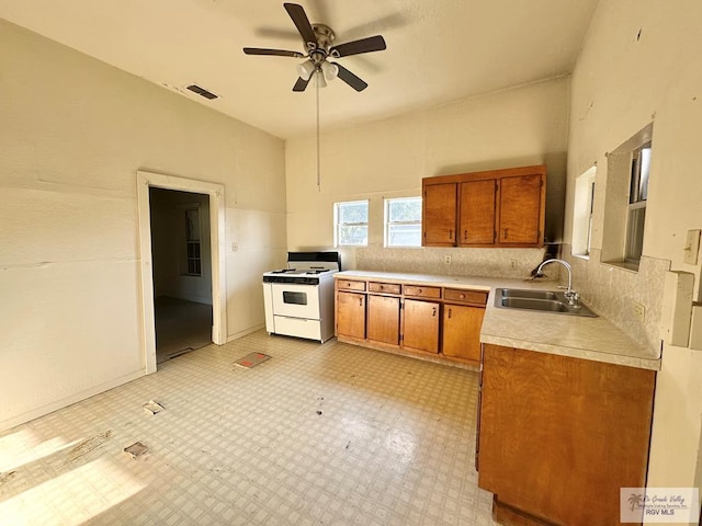 309 E Polk Ave, Harlingen, TX 78550 - kitchen featuring white gas range, a sink, brown cabinetry, light countertops, and ceiling fan
