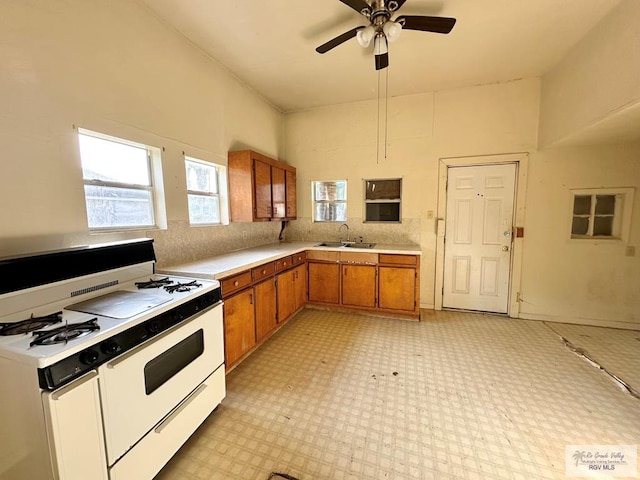 309 E Polk Ave, Harlingen, TX 78550 - kitchen with gas range gas stove, a sink, brown cabinetry, light countertops, and light floors