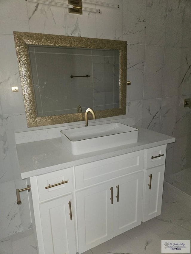 1115 Falcon Dr, Harlingen, TX 78550 - bathroom featuring marble look tiles, vanity, and tile walls
