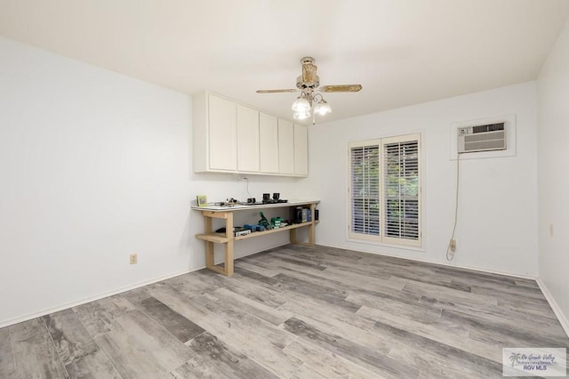 interior space with a wall mounted air conditioner, light wood-type flooring, and ceiling fan