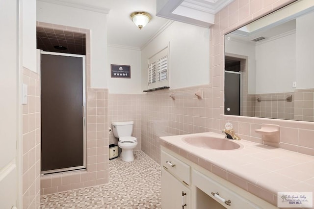 bathroom featuring vanity, a shower with door, ornamental molding, and tile walls