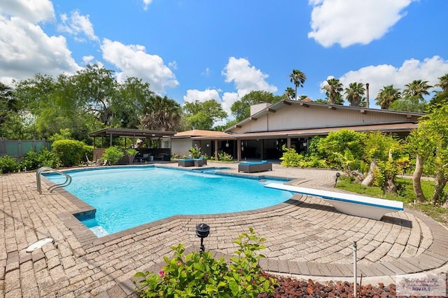 view of swimming pool with a diving board and a patio