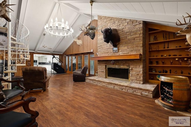 living room with lofted ceiling with beams, wood walls, a chandelier, wood-type flooring, and a fireplace