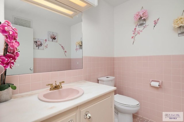 bathroom featuring tile patterned floors, vanity, toilet, and tile walls