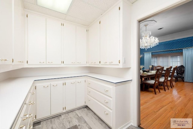 kitchen with light hardwood / wood-style floors, white cabinetry, and a notable chandelier