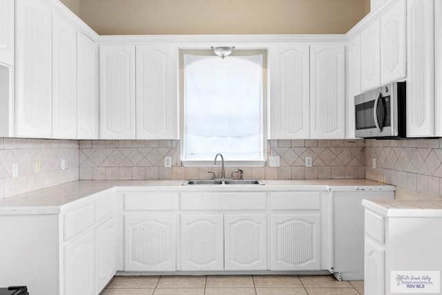 kitchen with light tile patterned floors, white cabinetry, and sink