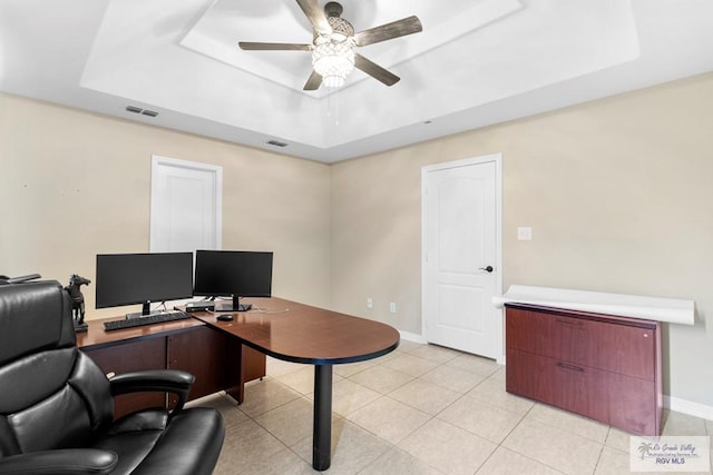 tiled office with a tray ceiling and ceiling fan